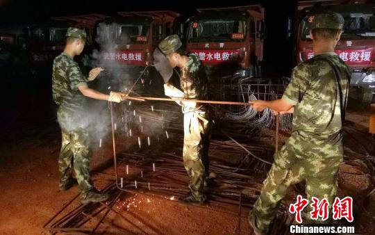 在堤坝附近的营地里，三大队九中队战士薛振兴和战友一起忙着焊接。火花飞溅，因焊接而产生的紫色烟雾弥漫在工地。一根根直径20毫米的钢筋，经战士们焊接后，形成一只长1.5米、宽1.2米、高1米的铁笼。 王昊阳 摄