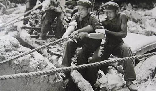 ▲在没有大型起重工具的情况下,解放军战士用双手拨开重物救人