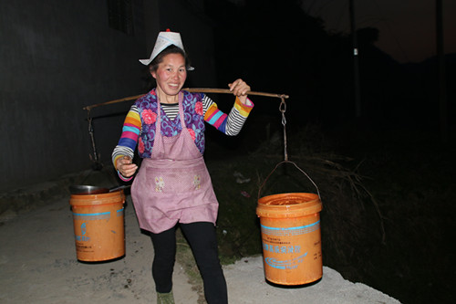 夜里，一名妇女好不容易排队舀得一担水后抬家来.JPG